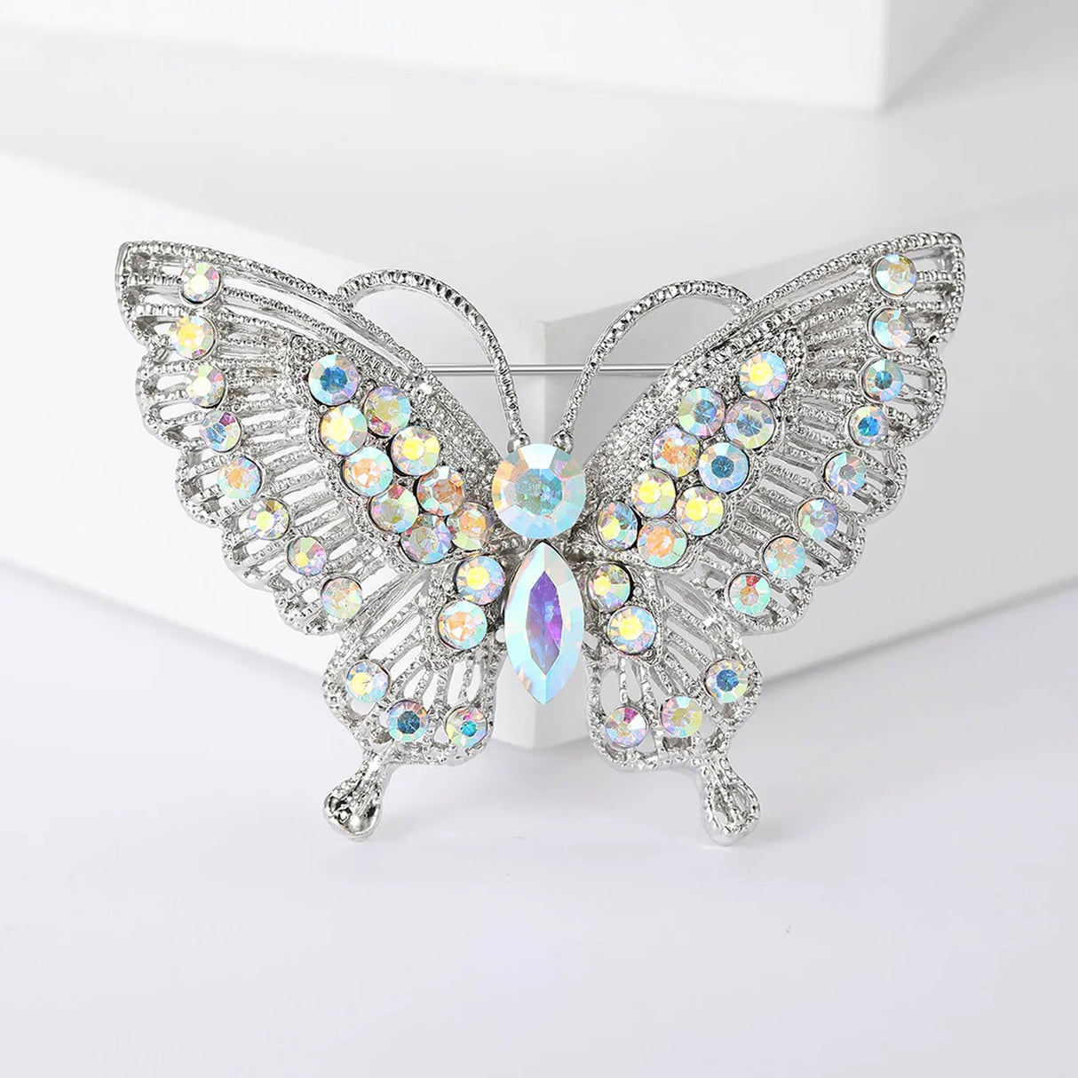 Butterfly brooch with silver-tone base, iridescent round and marquise-cut stones, front view on white block.