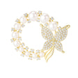 Butterfly brooch with gold-tone metal, round white faux pearls, and clear faceted stones in circular design, cutout on white.