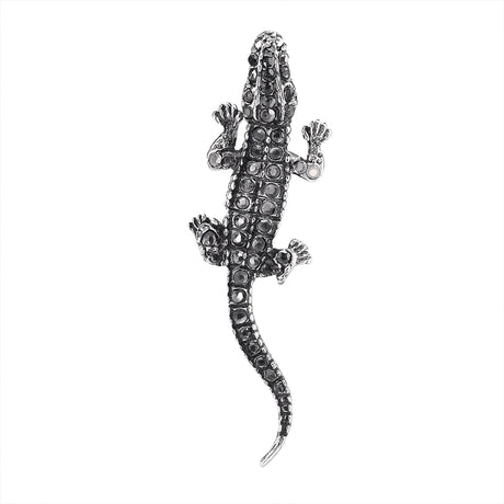 Lizard brooch with silver-tone metal finish and black faceted stones, top-down view, cutout on white background.