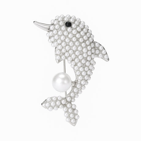 Dolphin brooch with silver-tone metal finish, covered in small white round beads, black eye detail, and suspended imitation pearl, cutout on white background.