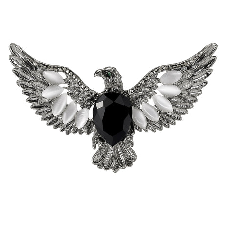 Eagle brooch with silver-tone finish, black faceted center stone, and white oval accent stones, cutout on white.