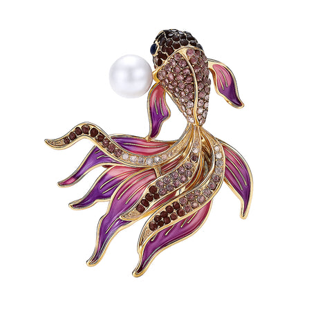 Fish brooch with gold-tone outline, purple faceted stones, pink-toned enamel fins, and white round bead, cutout on white.