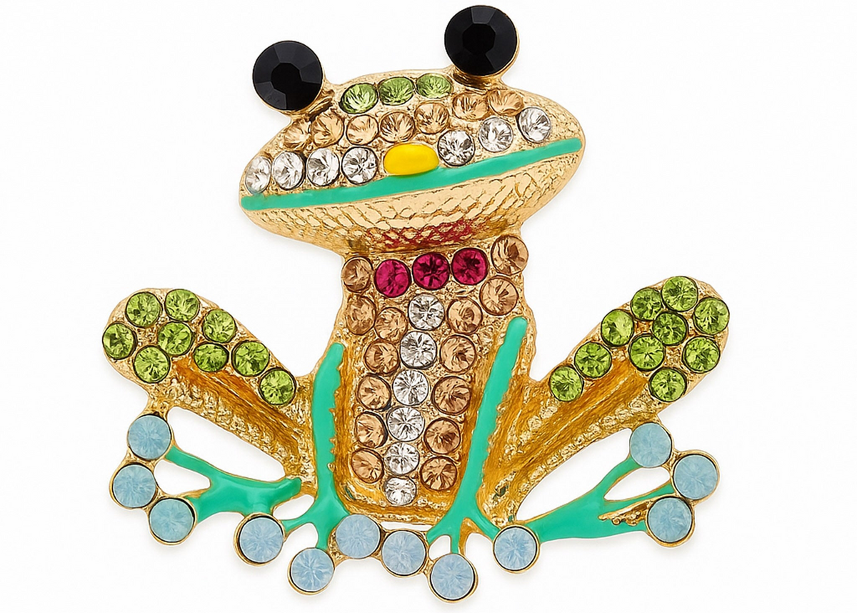 Frog brooch with gold-tone base, multicolor faceted stones, black eyes, and green enamel accents, cutout on white. Landscape crop for secondary use.