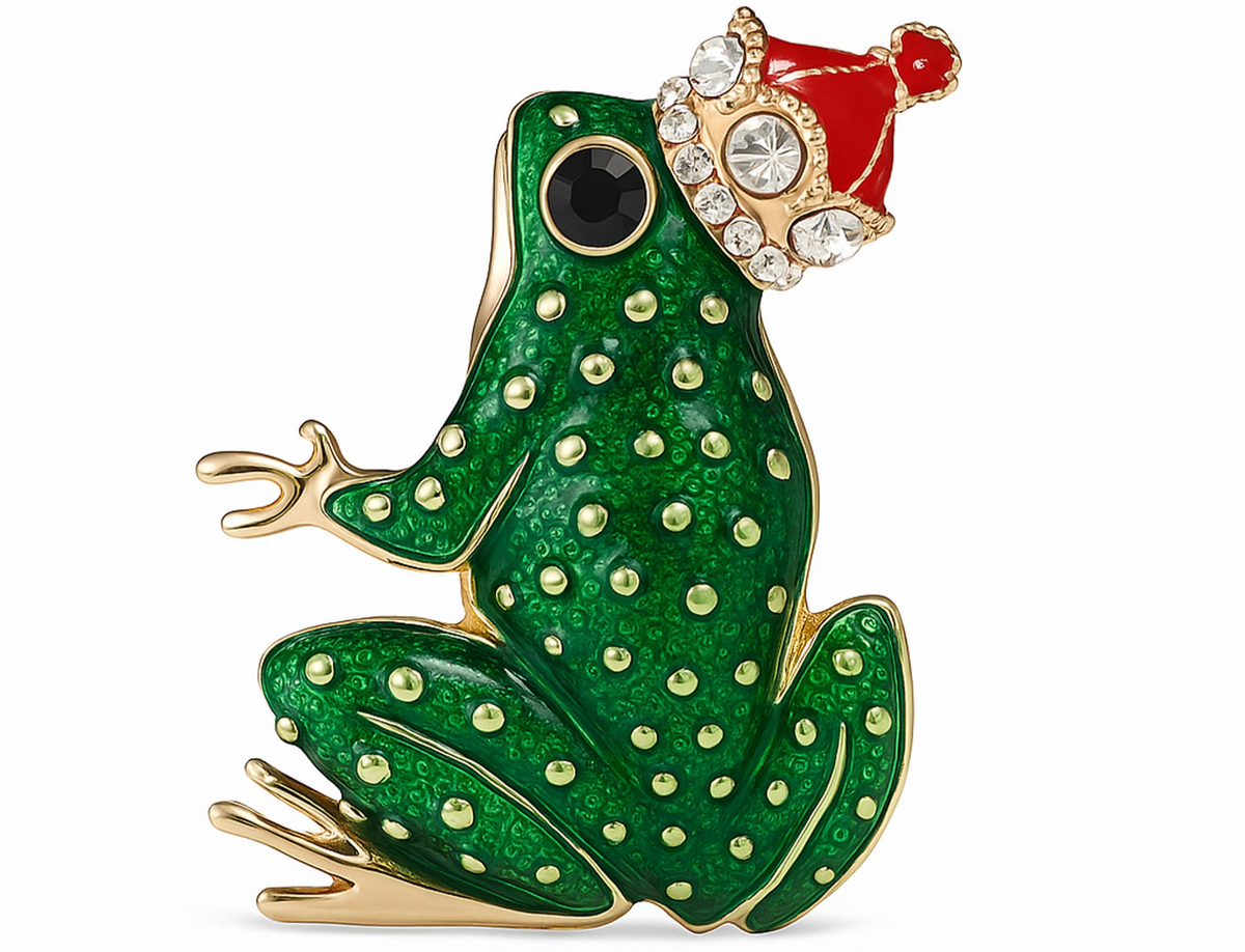 Green enamel frog brooch with gold-tone detailing, black eye, and red crown with clear faceted stones, cutout on white background. Landscape crop for secondary use.