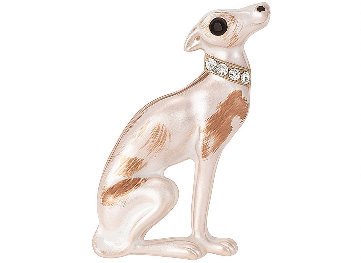 Sitting greyhound brooch with white body, brown enamel patches, black eye, and clear faceted stone collar, cutout on white. Landscape crop for secondary use.