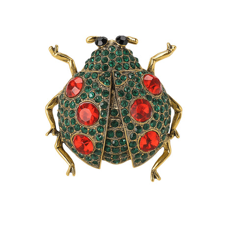 Ladybug brooch with gold-tone metal, green base, red faceted stones, and black eyes, cutout on white.