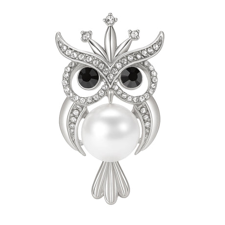 Owl brooch with silver-tone metal finish, eyes from black faceted stones, small clear crystal accents, and large white round imitation pearl body, cutout on white.
