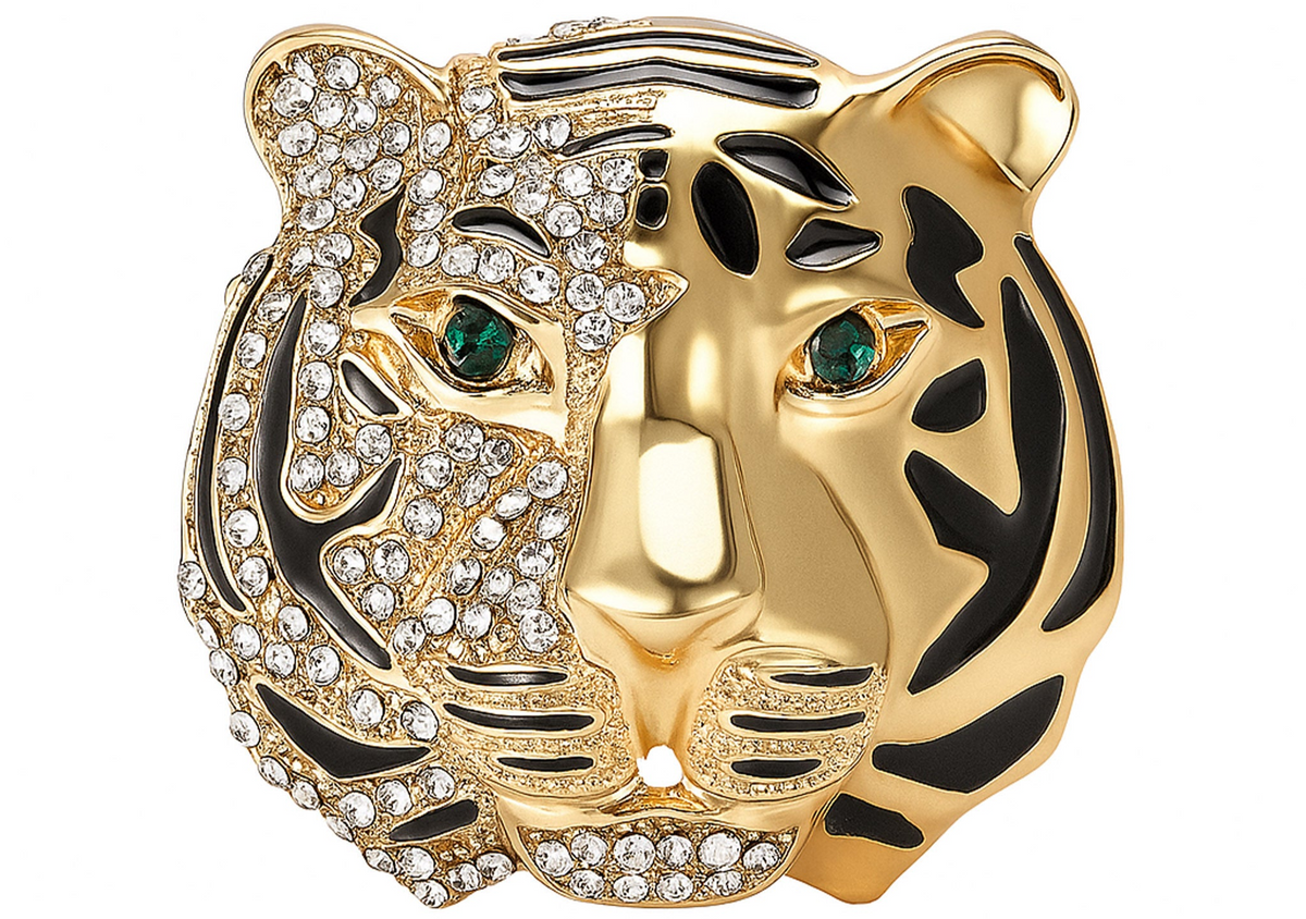 Tiger head brooch with gold-tone finish, half covered in clear faceted stones and black enamel stripes, green-tone eyes, cutout on white. Landscape crop for secondary use.