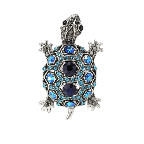 Tortoise brooch with silver-tone metal finish, dark blue center stones, and light blue faceted accents, cutout on white.
