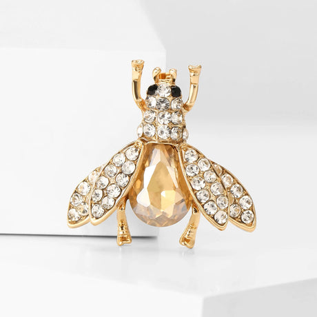 Bee brooch featuring clear faceted stones on wings and head, amber-toned body stone, upright pose on white background.