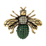 Bee brooch with antique gold-tone wings, clear stones on head, and green round clustered stones on body, cutout on white background.