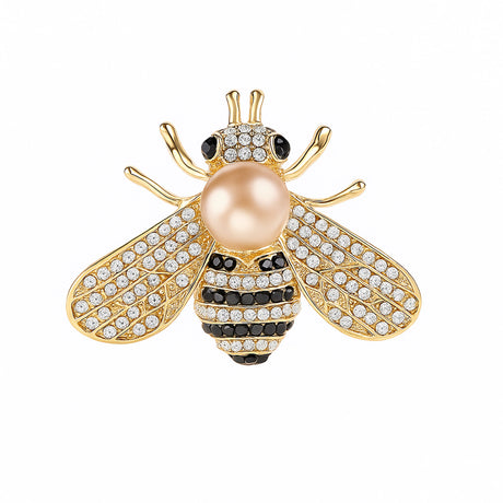 Bee brooch with gold-tone finish, clear faceted stones, black accents, and beig-pink round bead, cutout on white.