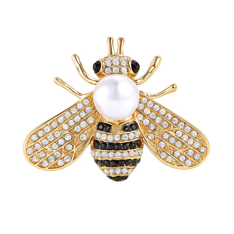 Bee brooch in gold-tone metal with clear stones, black striped details, and white round bead, cutout on white background.