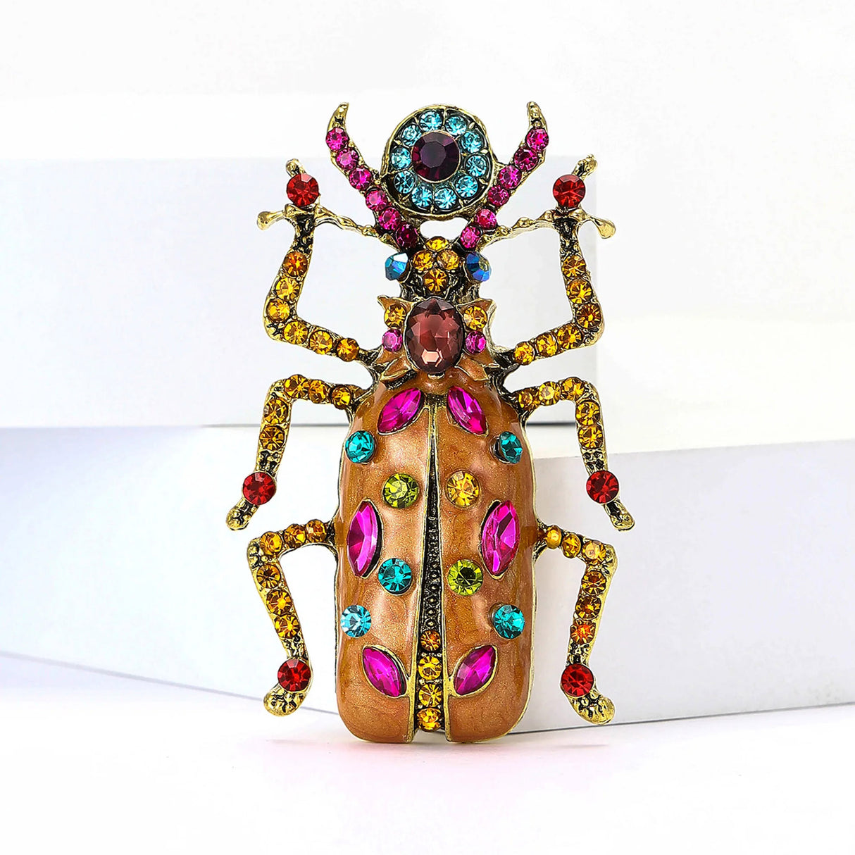 Beetle brooch with orange enamel body, accented by multicolor stones on wings, legs, and antennae, upright front view.