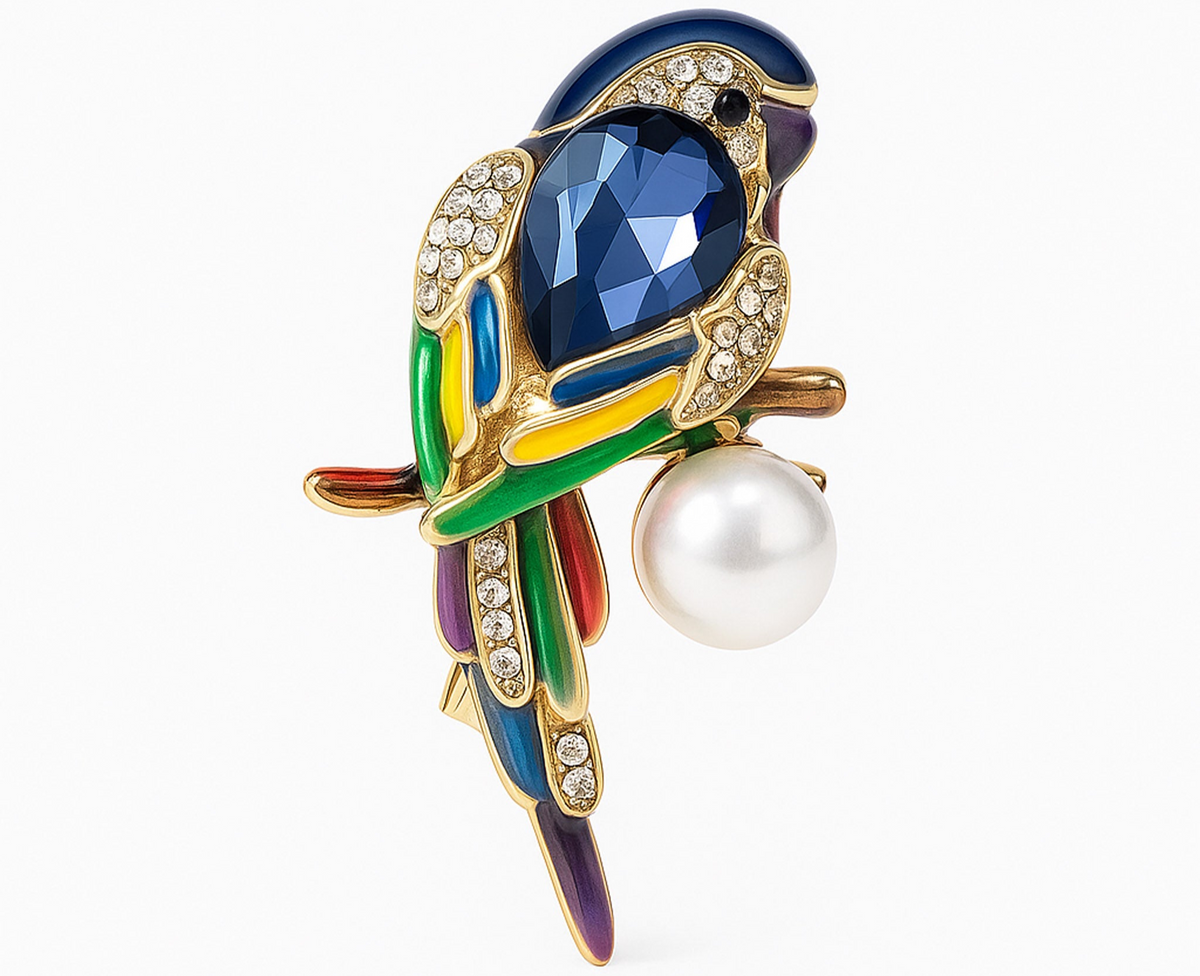 Parrot brooch with blue faceted stone, multicolor enamel accents, clear pavé stones, and round white imitation pearl, cutout on white. Landscape crop for secondary use.