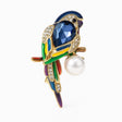 Parrot brooch with blue faceted stone, multicolor enamel accents, clear pavé stones, and round white imitation pearl, cutout on white.