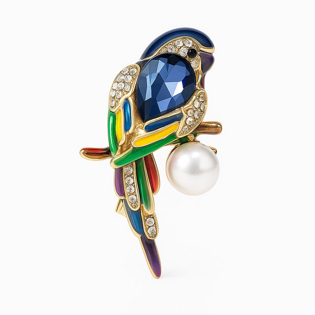 Parrot brooch with blue faceted stone, multicolor enamel accents, clear pavé stones, and round white imitation pearl, cutout on white.