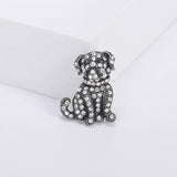 Bulldog brooch with clear faceted stones, black eyes, and iridescent collar on vintage-look silver-tone metal, upright front view on white platform.