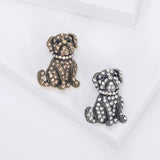 Two bulldog brooches side by side, one in brown stones on gold-tone metal, the other in clear stones on silver-tone metal. Flat lay studio view.