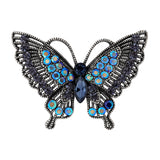 Butterfly brooch with dark metal base, black faceted stones with iridescent blue accents, cutout on white background.