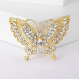 Butterfly brooch with gold-tone metal base, clear round and marquise-cut stones, front view on white block.