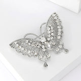 Butterfly brooch in silver-tone metal with clear round stones and marquise center stone, angled view on white.