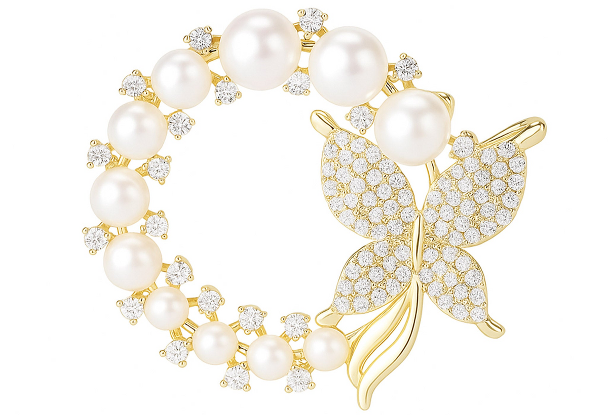 Butterfly brooch with gold-tone metal, round white faux pearls, and clear faceted stones in circular design, cutout on white. Landscape crop for secondary use.