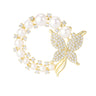 Butterfly brooch with gold-tone metal, round white faux pearls, and clear faceted stones in circular design, cutout on white.