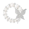Butterfly brooch with silver-tone metal, white round imitation pearls, and clustered clear stones in a circle shape, cutout on white.