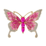 Butterfly brooch with pink enamel wings, gold-tone metal frame, small clear round stones along edges, and three large pink oval faceted stones as the body, cutout on white.