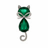 Cat brooch with green faceted stones, silver-tone bow detail, and spiral tail adorned with clear stones, cutout on white.