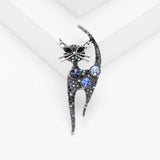 Cat brooch covered in round blue-toned stones, set in vintage style silver-tone metal base, displayed on white platform in studio.