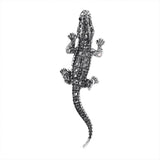Lizard brooch with silver-tone metal finish and black faceted stones, top-down view, cutout on white background.