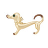 Ddachshund dog brooch with brushed gold-tone finish, brown detailing, green faceted eye, and gold-tone bow, cutout on white background.