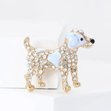 Dog brooch in gold-tone metal finish with light blue enamel accents and clear stones, standing upright on white block.