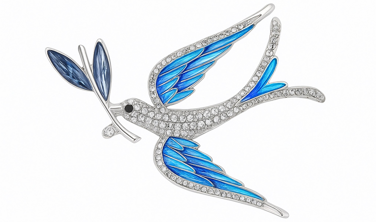 Dove brooch with blue-toned wings, clear faceted stones on body, and blue leaf detail, cutout on white background. Landscape crop for secondary use.