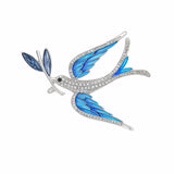 Dove brooch with blue-toned wings, clear faceted stones on body, and blue leaf detail, cutout on white background.