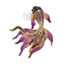 Fish brooch with gold-tone outline, purple faceted stones, pink-toned enamel fins, and white round bead, cutout on white.