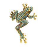 Frog brooch in gold-tone metal frame, studded with small round green stones with multicolor accents. Cutout on white.