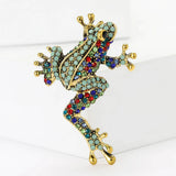 Frog brooch with gold-tone frame, turquoise and multicolor pave-set stones, upright on white block in studio.