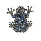 Frog brooch with dark silver-tone finish, decorated with blue and navy faceted stones, cutout on white background.