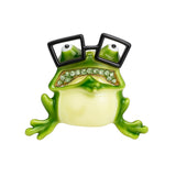 Frog brooch with green enamel body, black square glasses, and green faceted stone mouth, cutout on white.