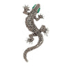 Gecko lizard brooch with silver-tone metal finish, gray faceted stones, and green eyes, cutout on white background.