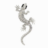 Gecko lizard brooch with silver-tone metal finish, iridescent clear faceted stones, and black eyes, cutout on white background.