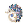 Hedgehog brooch in gold-tone metal with clear faceted stones and marquise stones in blue and purple, cutout on white.