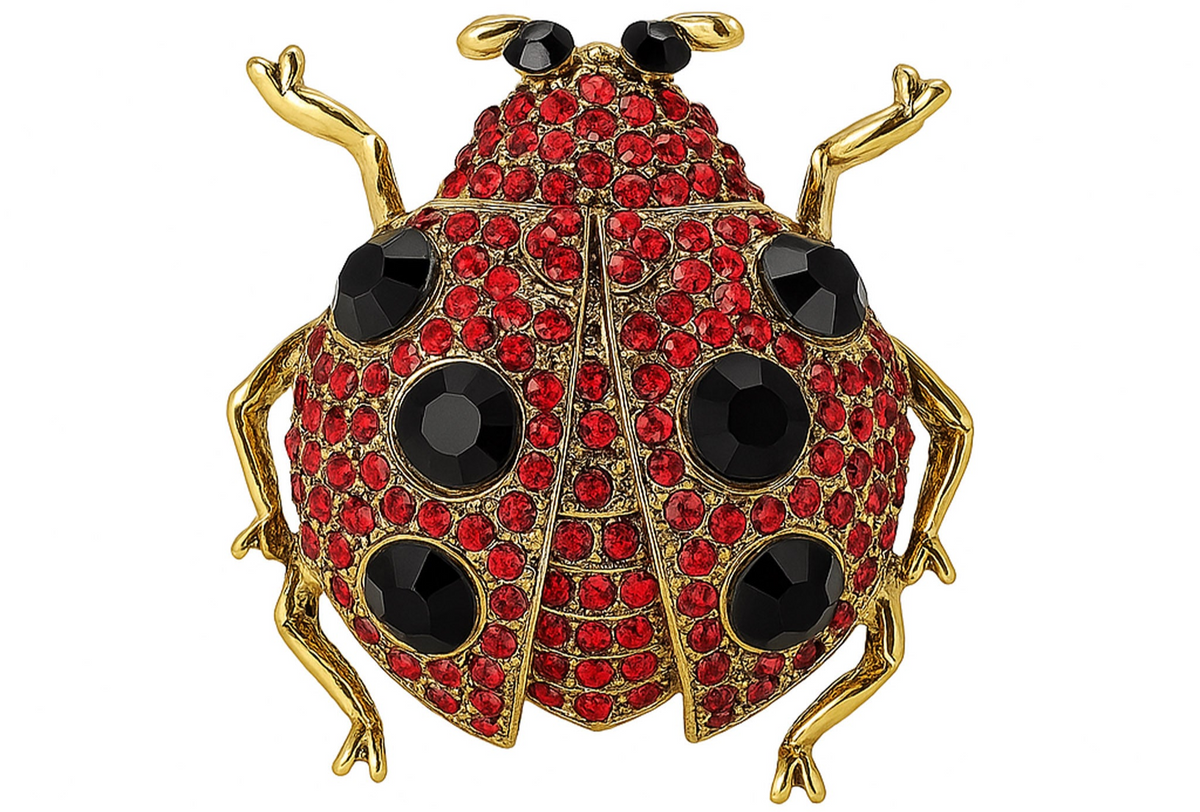 Ladybird brooch with gold-tone metal, red base, black faceted stones, and black eyes, cutout on white. Landscape crop for secondary use.