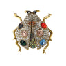 Ladybird brooch with gold-tone metal, clear faceted stones, multicolor accents, and black eyes, cutout on white.