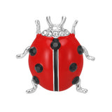 Ladybird brooch with red enamel finish, black faceted dots, clear accent stones, and silver-tone legs, cutout on white.