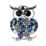 Owl brooch with silver-tone finish, blue faceted stones, black round eyes, and white crystal accents, cutout on white.