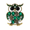 Owl brooch with gold-tone finish, large green faceted stones, black round eyes, and small multicolor rhinestone accents. Cutout on white.